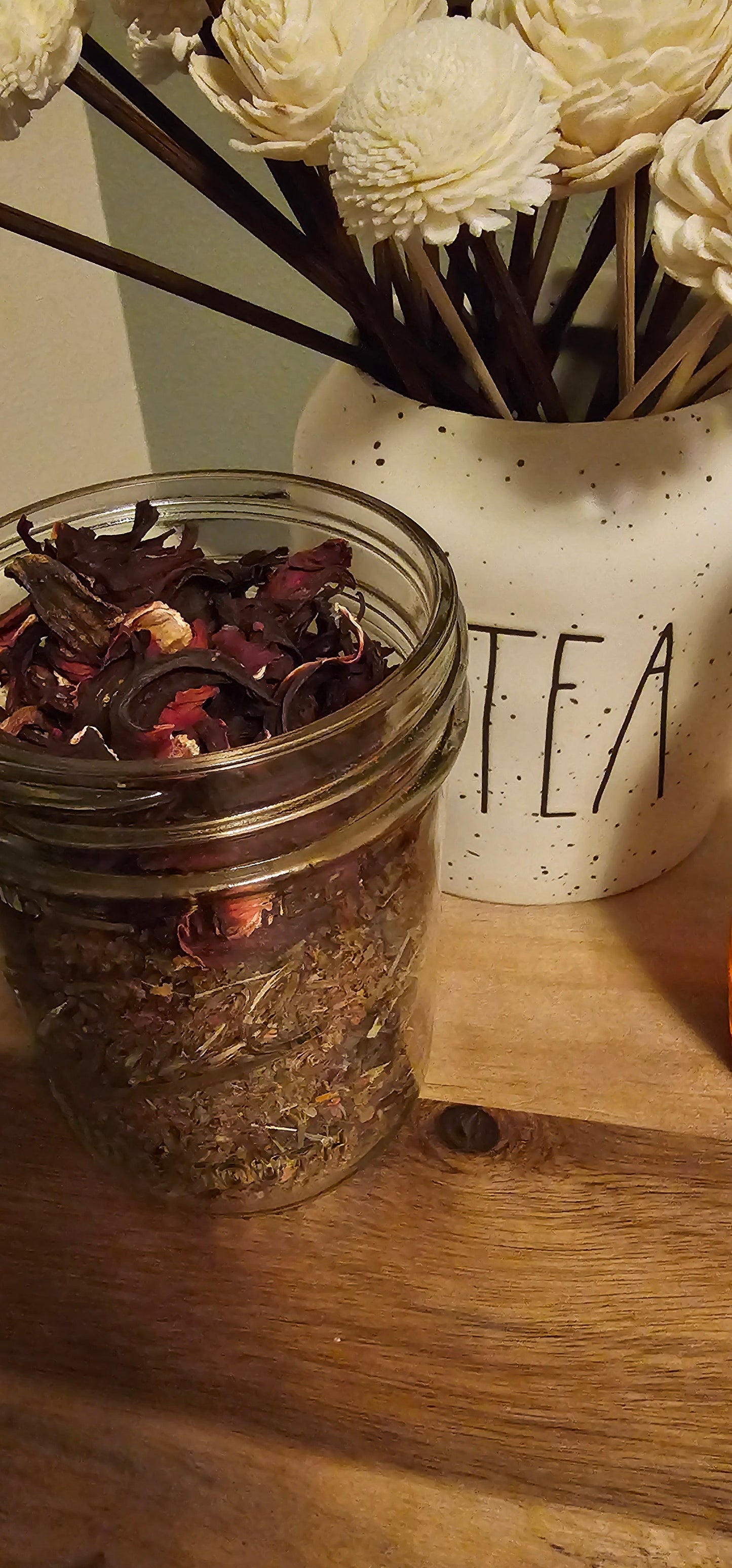 Loose leaves in a mason jar on a wood table with decor and honey