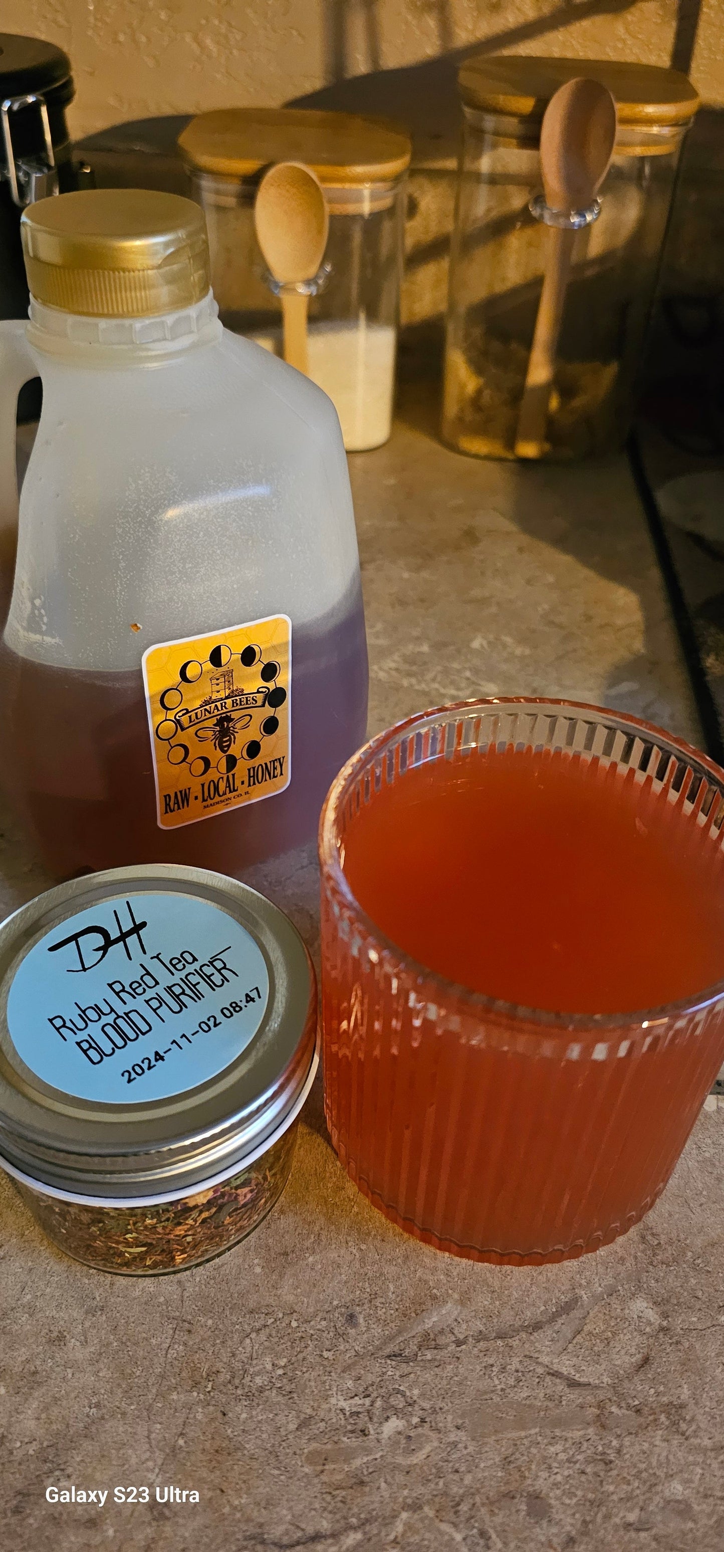 Brewed red liquid in a glass cup on a wood table with decor and honey