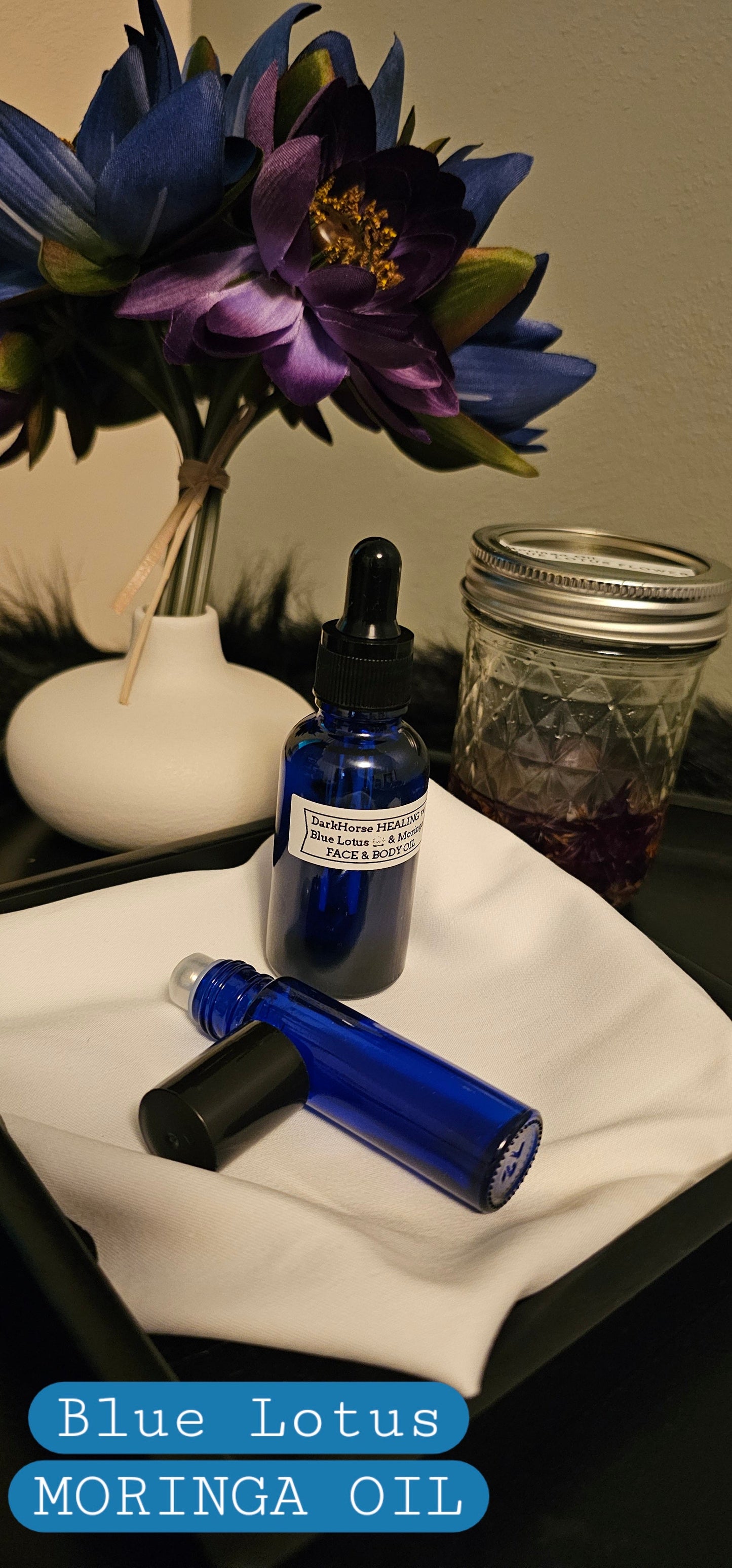 Blue Lotus Moringa Oil bottles with flowers and jars on a tray.