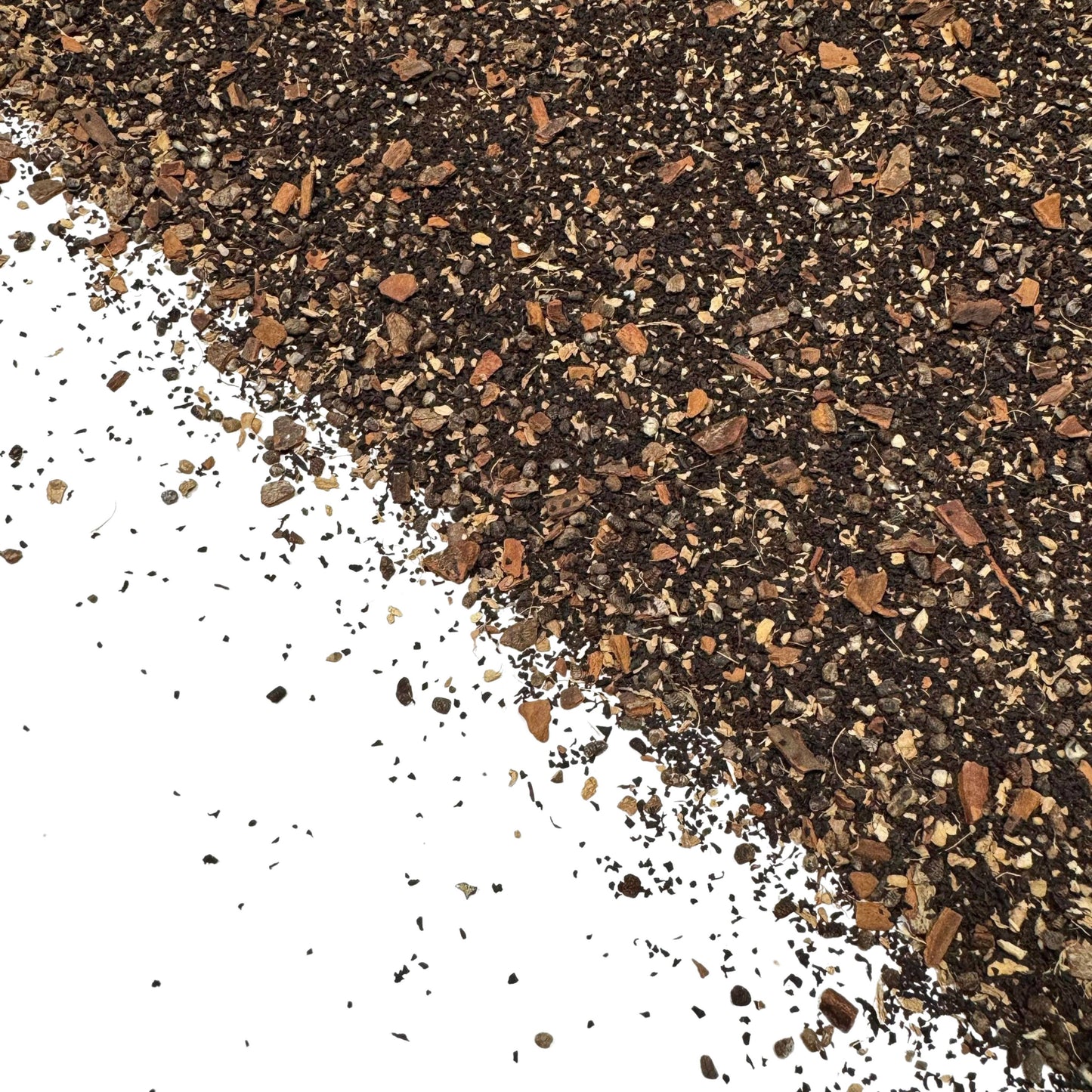 close-up of loose chai tea blend with black tea leaves and spices like cinnamon and cardamom on white background