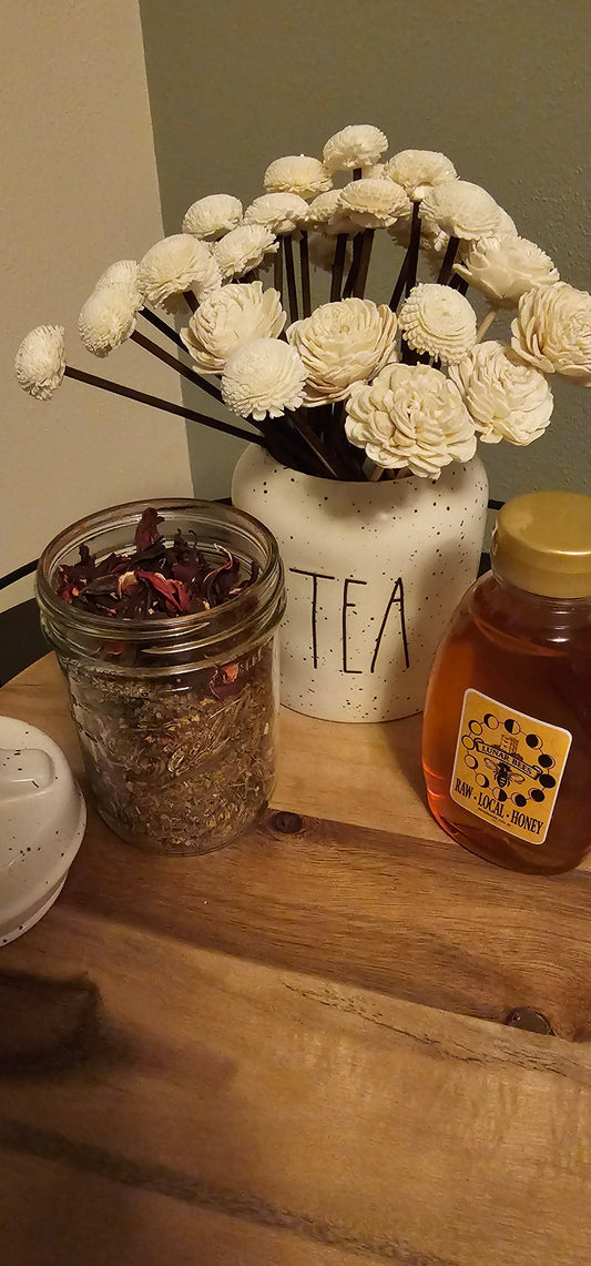Loose leaves in a mason jar on a wood table with decor and honey