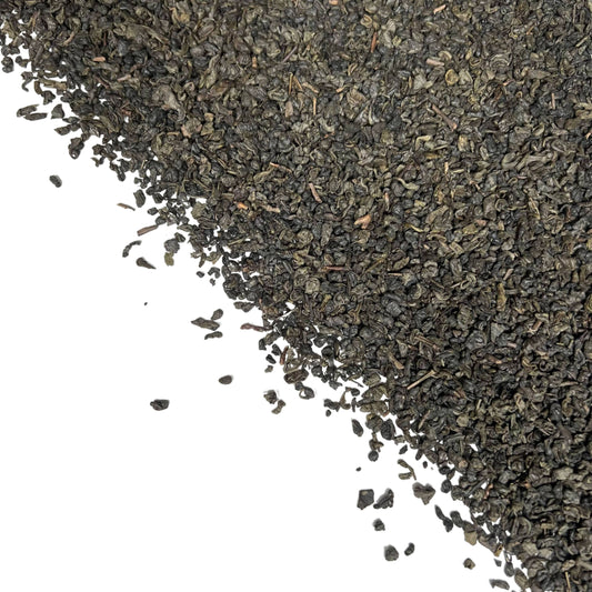 Close-up of dried tightly rolled Gunpowder green tea leaves in bulk on a white background
