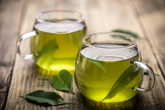 Two cups of Vital Green Blend tea with matcha and mint on a rustic wooden table.
