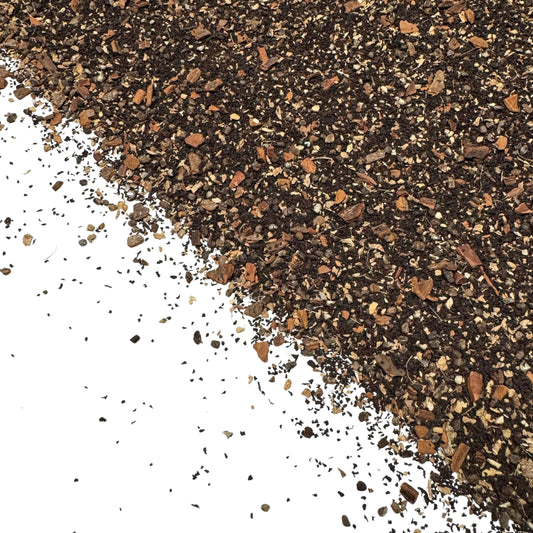close-up of loose chai tea blend with black tea leaves and spices like cinnamon and cardamom on white background